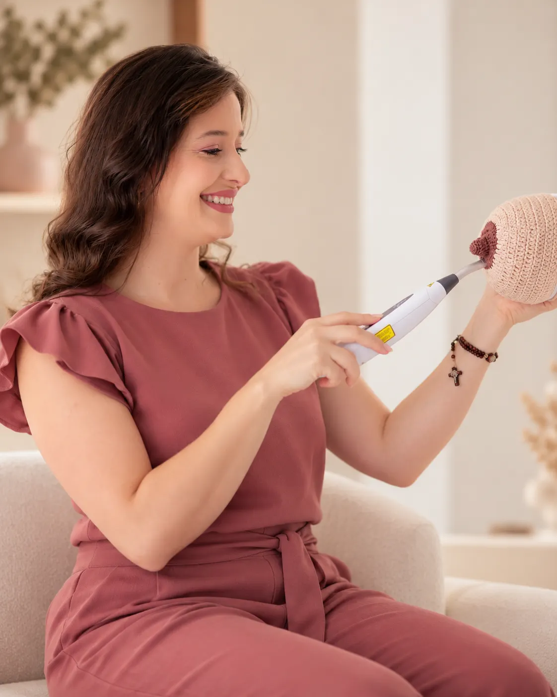 Thaissa Vargas demonstrando o aparelho de laserterapia num modelo de mama em crochê