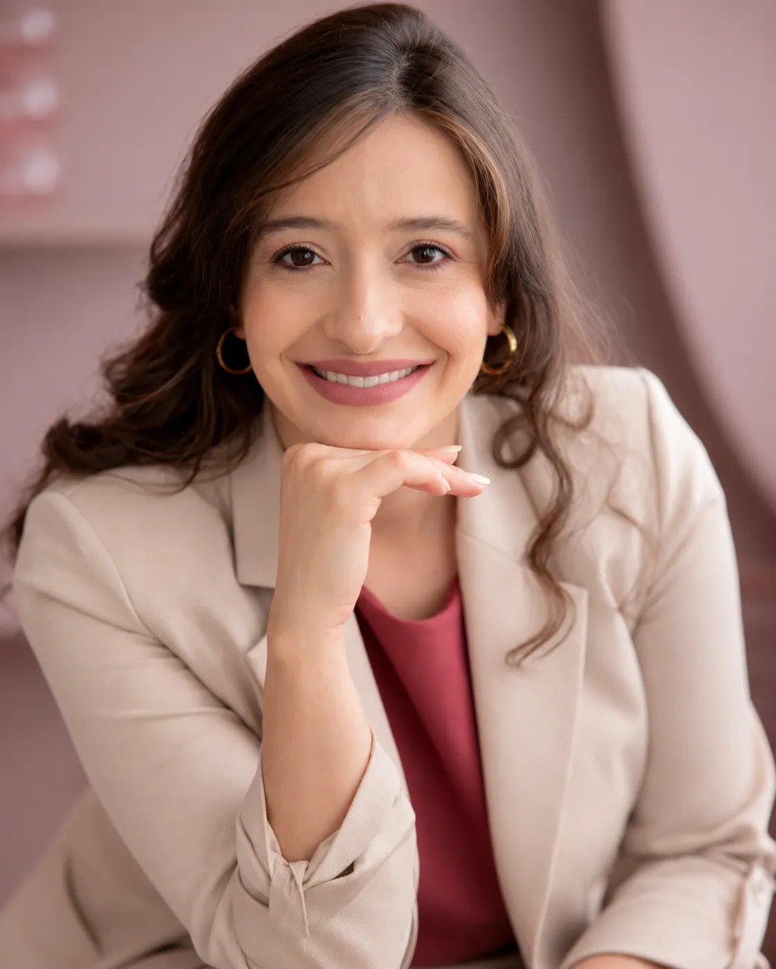 Retrato de Thaissa Vargas sorrindo, de blazer bege, em fundo rosado